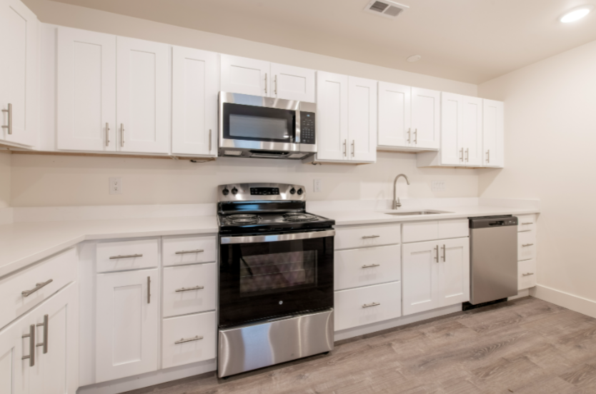 A modern kitchen with white cabinets and stainless steel appliances.